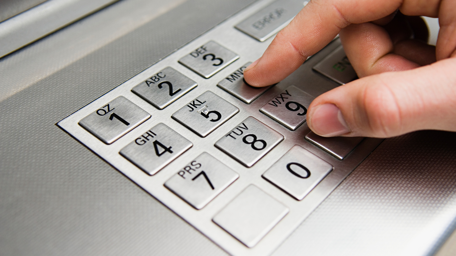 Hand at ATM keyboard.