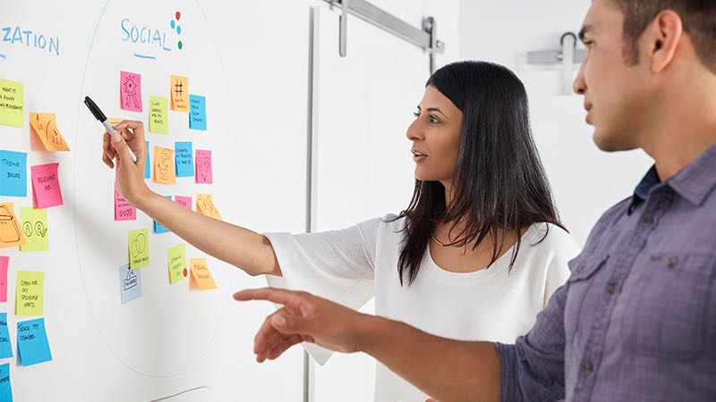 grow-your-business-with-us-800x450 Man and woman brainstorming at Scrum task board.